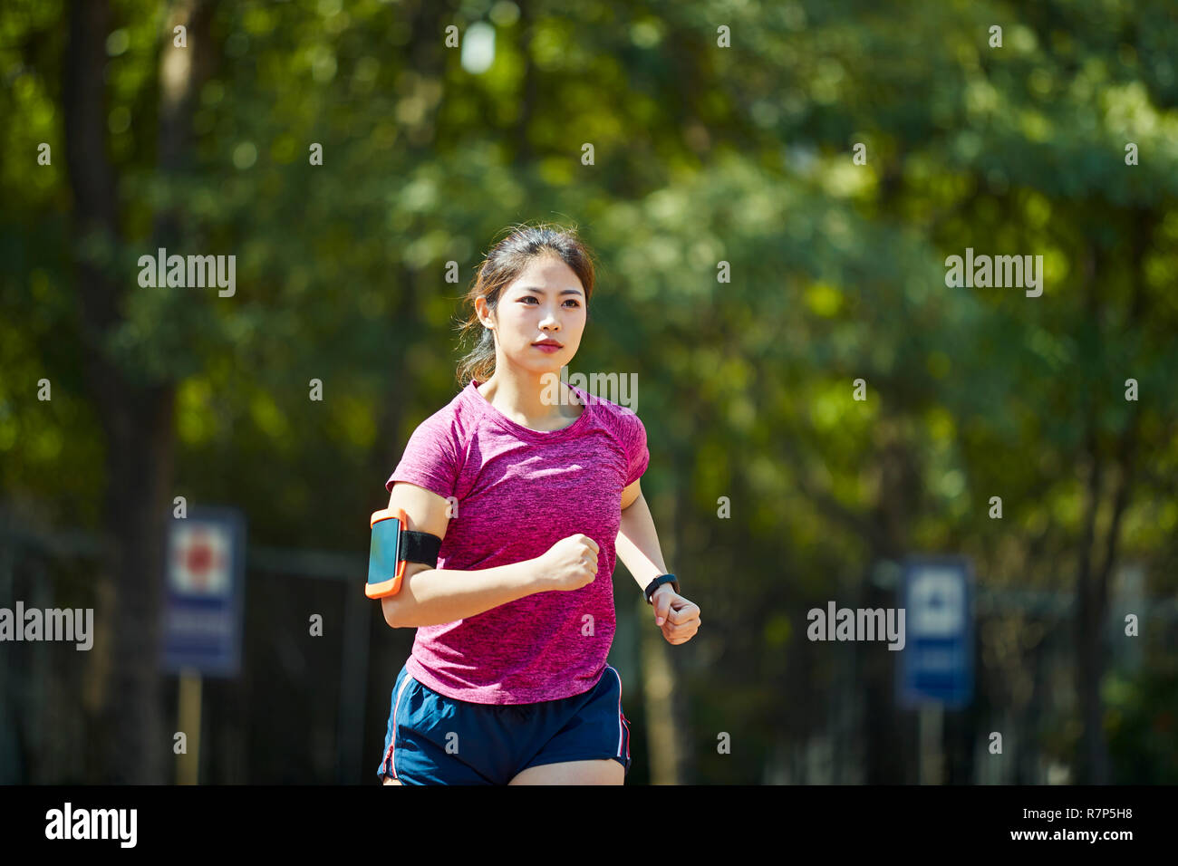 Giovane donna asiatica via e un campo sportivo in esecuzione Foto Stock