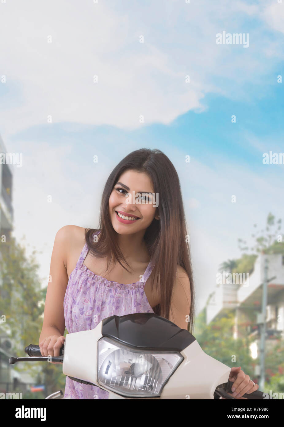 Ritratto di un sorridente giovane donna in posa con uno scooter. Foto Stock