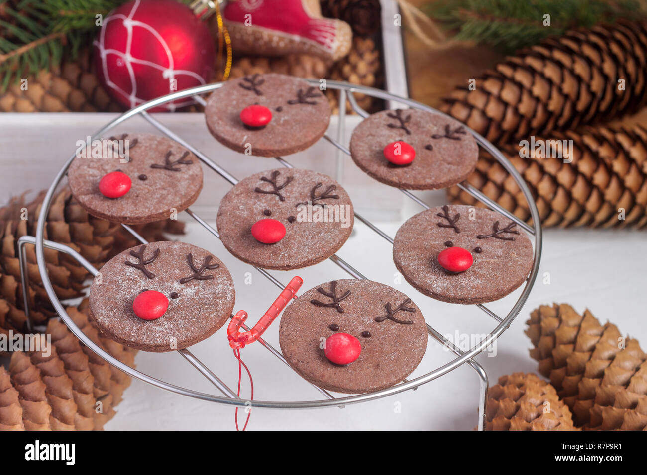 Festa del cioccolato cookie nella forma di un cervo Rudolph con un naso rosso circondato da decorazioni festive. Foto Stock