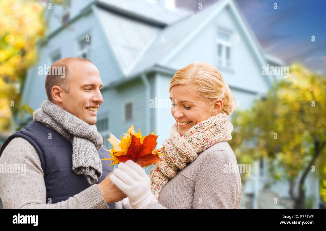 Coppia sorridente con autunno foglie di acero su house Foto Stock