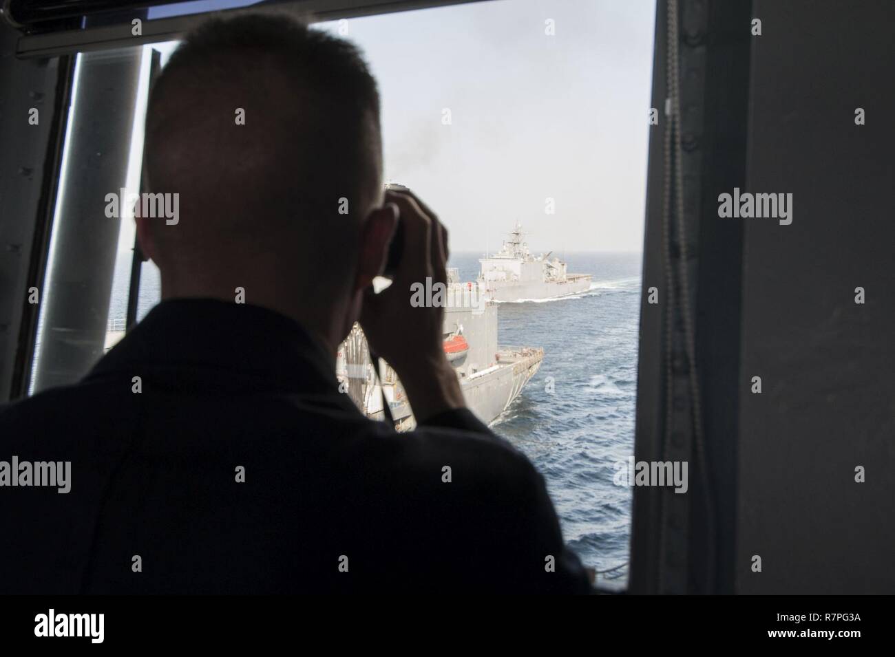 Mare Arabico (17 marzo 2017) USS Makin Island (LHD 8) Delegato Capt. David Oden osserva il dock anfibio sbarco nave USS Comstock (LSD 45) man mano che si avvicina la flotta oliatore di rifornimento USNS Walter S. Diehl (T-AO 193) durante un rifornimento in mare. Makin Island è distribuito negli Stati Uniti Quinta Flotta area di operazioni a sostegno della sicurezza marittima operazioni destinate a rassicurare gli alleati e partner e preservare la libertà di navigazione e il libero flusso di commercio nella regione. Foto Stock