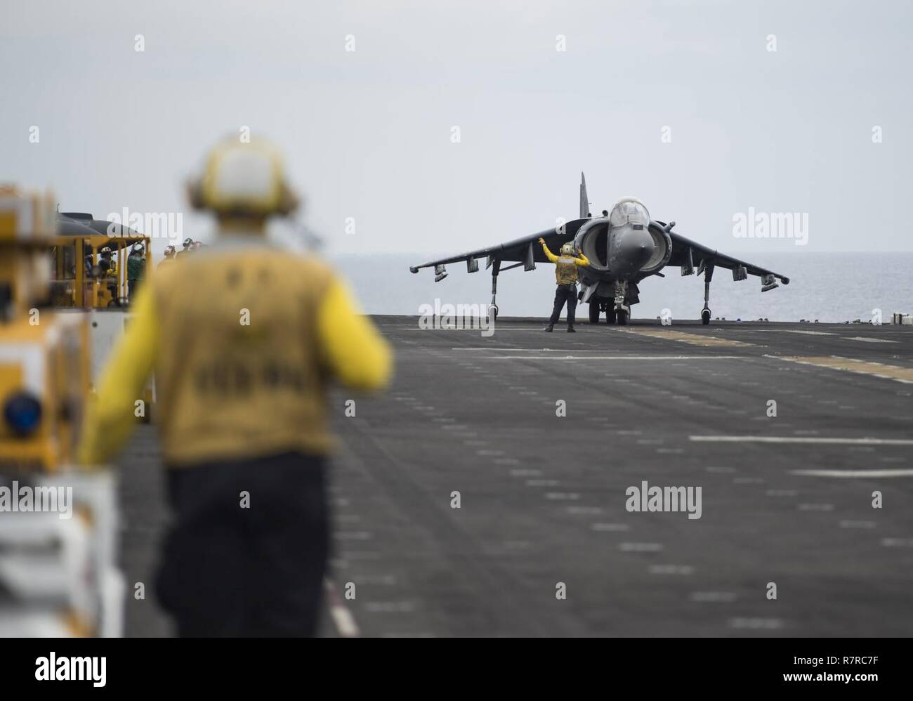 (29 marzo 2017) di aviazione di Boatswain Mate (manipolazione) 2a classe Christopher Diehl, da York, Pa., sinistra, si erge come un AV-8B Harrier, assegnato alla cresta guide scorrevoli del mezzo marino Tiltrotor Squadron (VMM) 163, taxi in posizione per il decollo sul ponte di volo dell'assalto anfibio nave USS Makin Island (LHD 8). Makin Island, l'ammiraglia per il Makin Island pronta anfibio Gruppo, con l'avviato undicesimo Marine Expeditionary Unit, è operativo in Indo-Asia-regione del Pacifico per migliorare la capacità di anfibio con i partner regionali e per servire come una pronta risposta in vigore per qualsiasi tipo di c Foto Stock