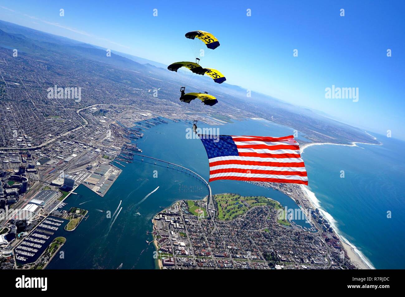 SAN DIEGO (29 marzo 2017) i membri dell'U.S. Navy parachute team di dimostrazione, il salto delle rane, eseguire una formazione di diamante come essi presente la Star-Spangled Banner durante una dimostrazione di formazione sopra la USS Midway Museum. Il salto delle rane sono basati in San Diego e antenna di eseguire dimostrazioni di paracadute intorno alla nazione a sostegno del Naval Special Warfare Marina e del reclutamento del personale. Foto Stock