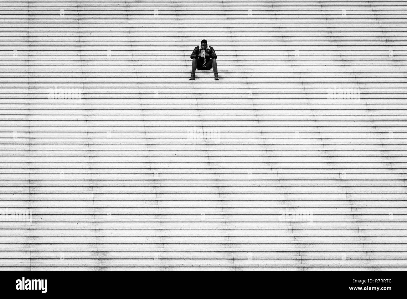 Lone ragazzo seduto sui gradini, a La Defense area in Parigi, Francia Foto Stock