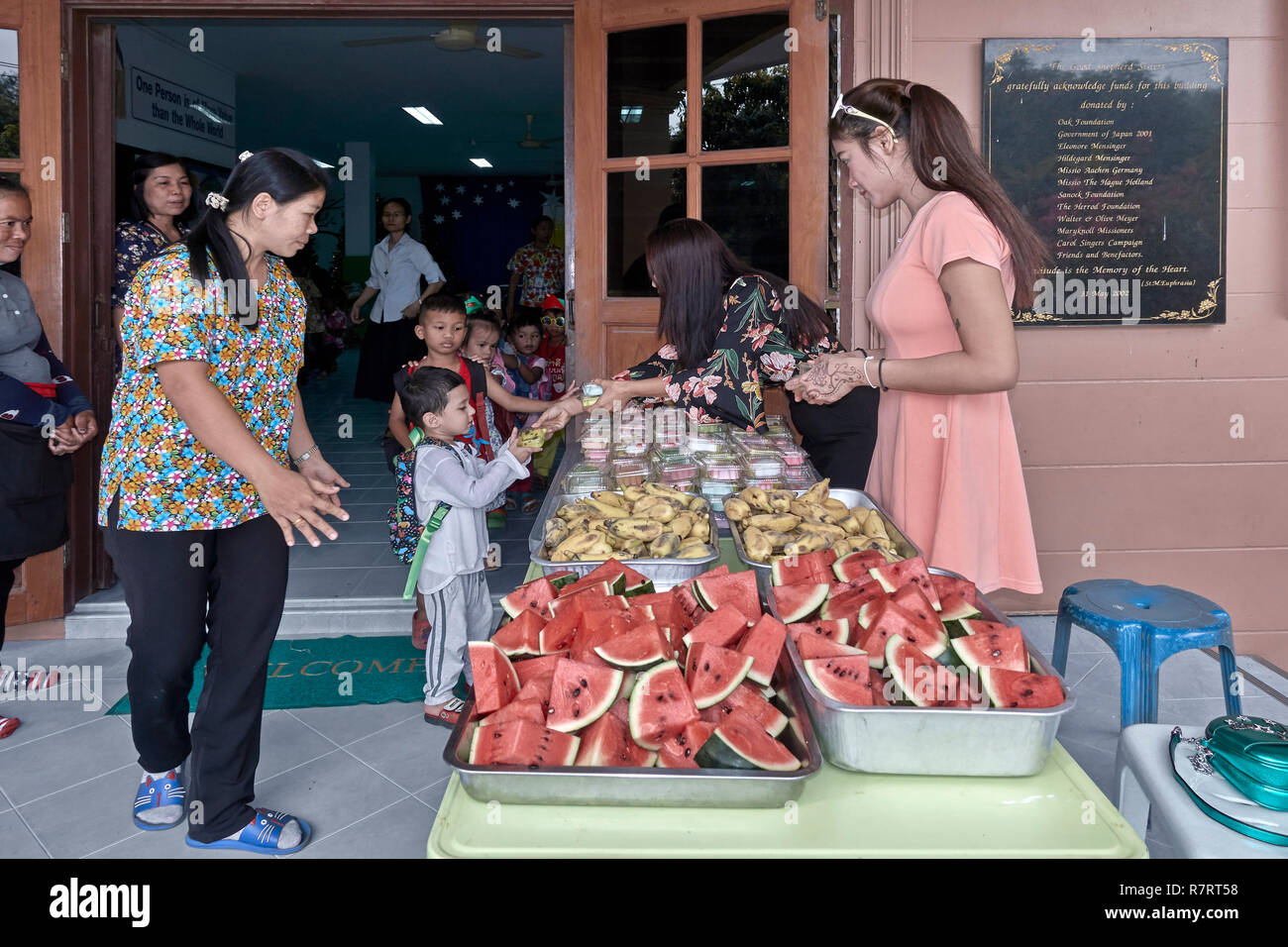 Centro di assistenza bambini per bambini svantaggiati con assistenti che danno cibo ai bambini. Thailandia Sud-est asiatico Foto Stock