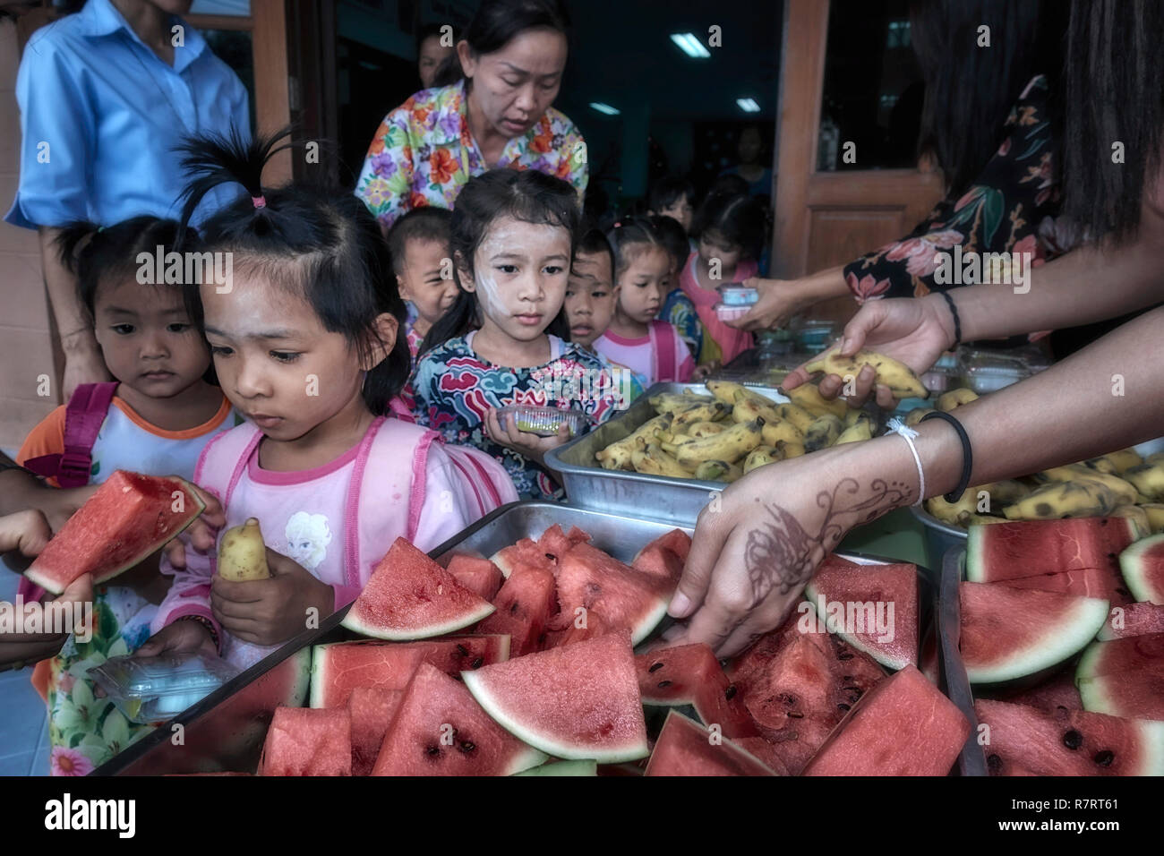 Centro di assistenza bambini per bambini svantaggiati con assistenti che danno cibo ai bambini. Thailandia Sud-est asiatico Foto Stock
