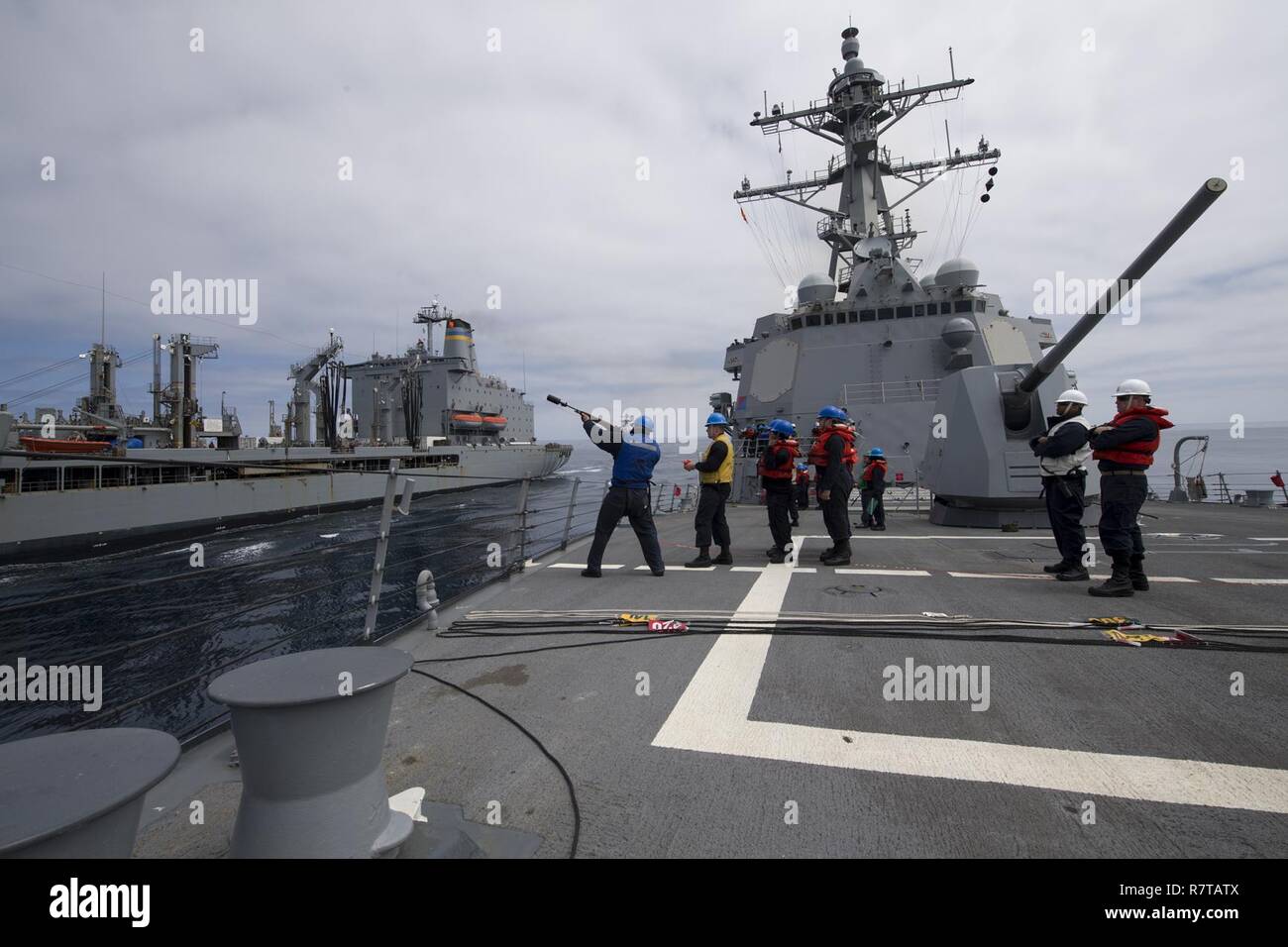 Oceano Pacifico (4 aprile 2017) velisti assegnati al Arleigh Burke-class guidato-missile destroyer USS Sterett (DDG 104) fire una linea di tiro dell'Henry J. Kaiser-class flotta oliatore di rifornimento USNS Yukon (T-AO-202) durante un rifornimento in mare. Sterett è parte della superficie Sterett-Dewey Action Group, operanti sotto il comando ed il controllo costrutto denominato 3a flotta in avanti. Foto Stock
