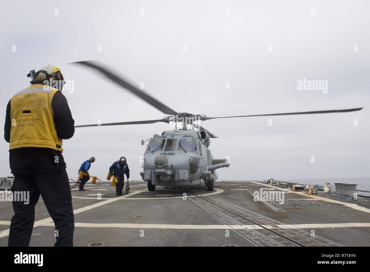 Oceano Pacifico (5 aprile 2017) marinai a bordo Arleigh Burke-class guidato-missile destroyer USS Sterett (DDG 104) preparare alla guarnitura e catena un MH-60R elicottero assegnato all'elicottero Maritime Strike Squadron (HSM) 49. Sterett è parte della superficie Sterett-Dewey Action Group ed è il terzo gruppo di distribuzione che operano sotto il comando ed il controllo costrutto denominato 3a flotta in avanti. Stati Uniti 3a flotta operante in avanti offre opzioni aggiuntive per la flotta del Pacifico commander sfruttando le capacità del 3° e 7° flotte. Foto Stock
