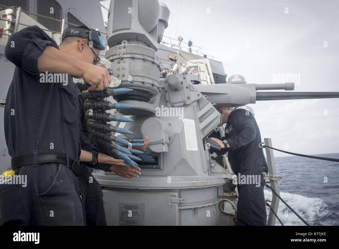 Sul mare del sud della Cina (5 aprile 2017) velisti assegnati al Arleigh Burke-class guidato-missile destroyer USS Stethem (DDG 63) carico e rendere pronta la porta MK 38 25mm machine-gun prima di un'esercitazione a fuoco. Stethem è di pattuglia nel Mare della Cina del Sud il supporto di sicurezza e stabilità nella Indo-Asia-regione del Pacifico. Foto Stock