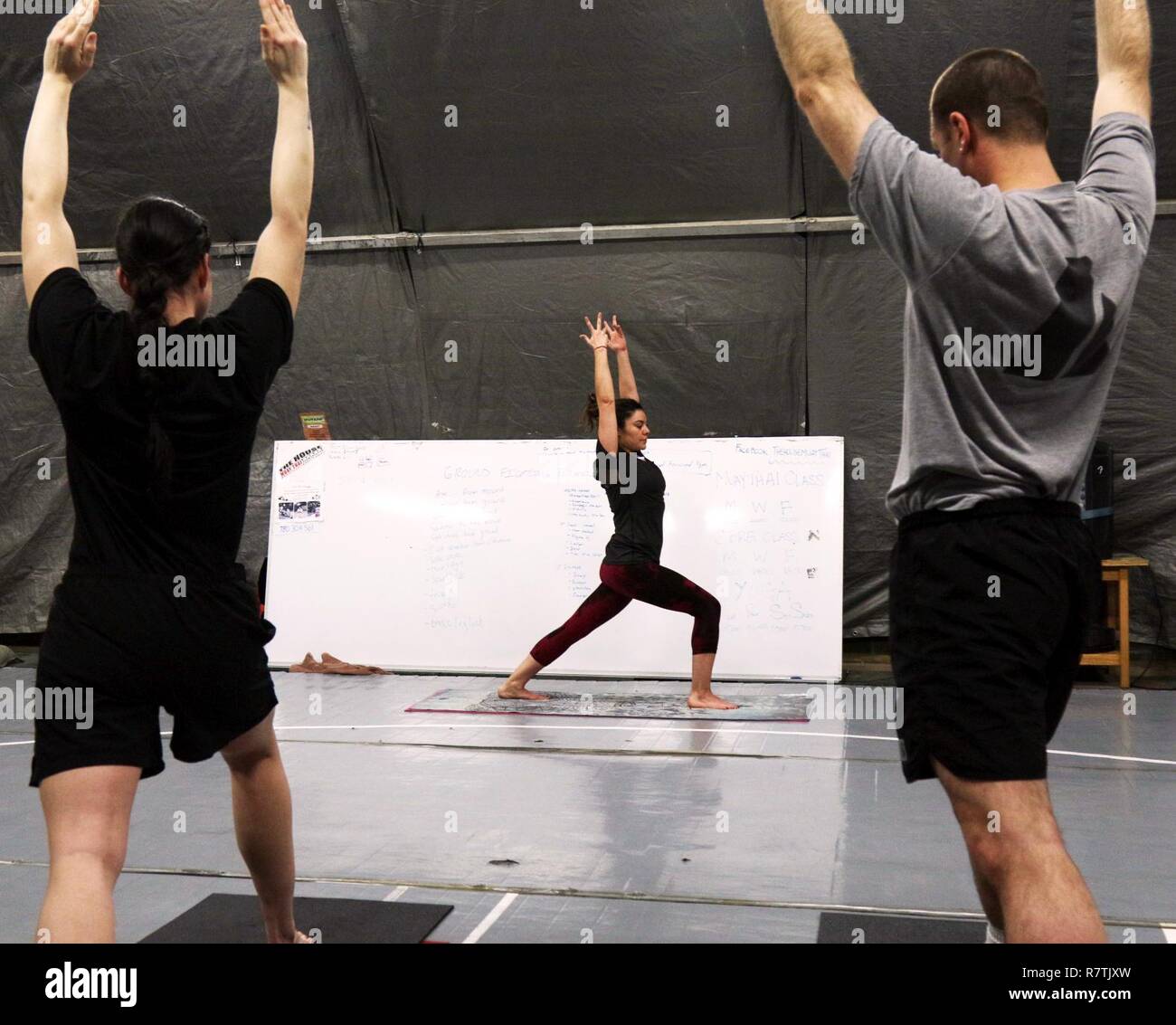 Heather Svizz, un analista di intelligence per la difesa multinazionale azienda, BAE Systems Inc., conduce i soldati in una classe di yoga a Bagram Airfield (BAF), Afghanistan. Svizz, da Los Lunas, NM, opere in prima divisione di cavalleria sostegno deciso supporto brigata ufficio di intelligence a BAF e volontari come un istruttore di yoga. Foto Stock