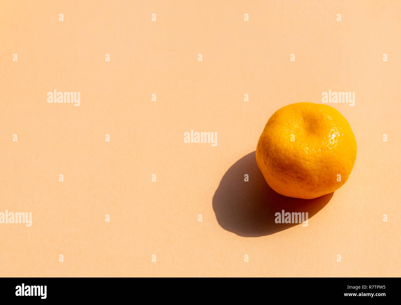 Un intero arance con forte ombra su sfondo arancione, spazio di copia Foto Stock