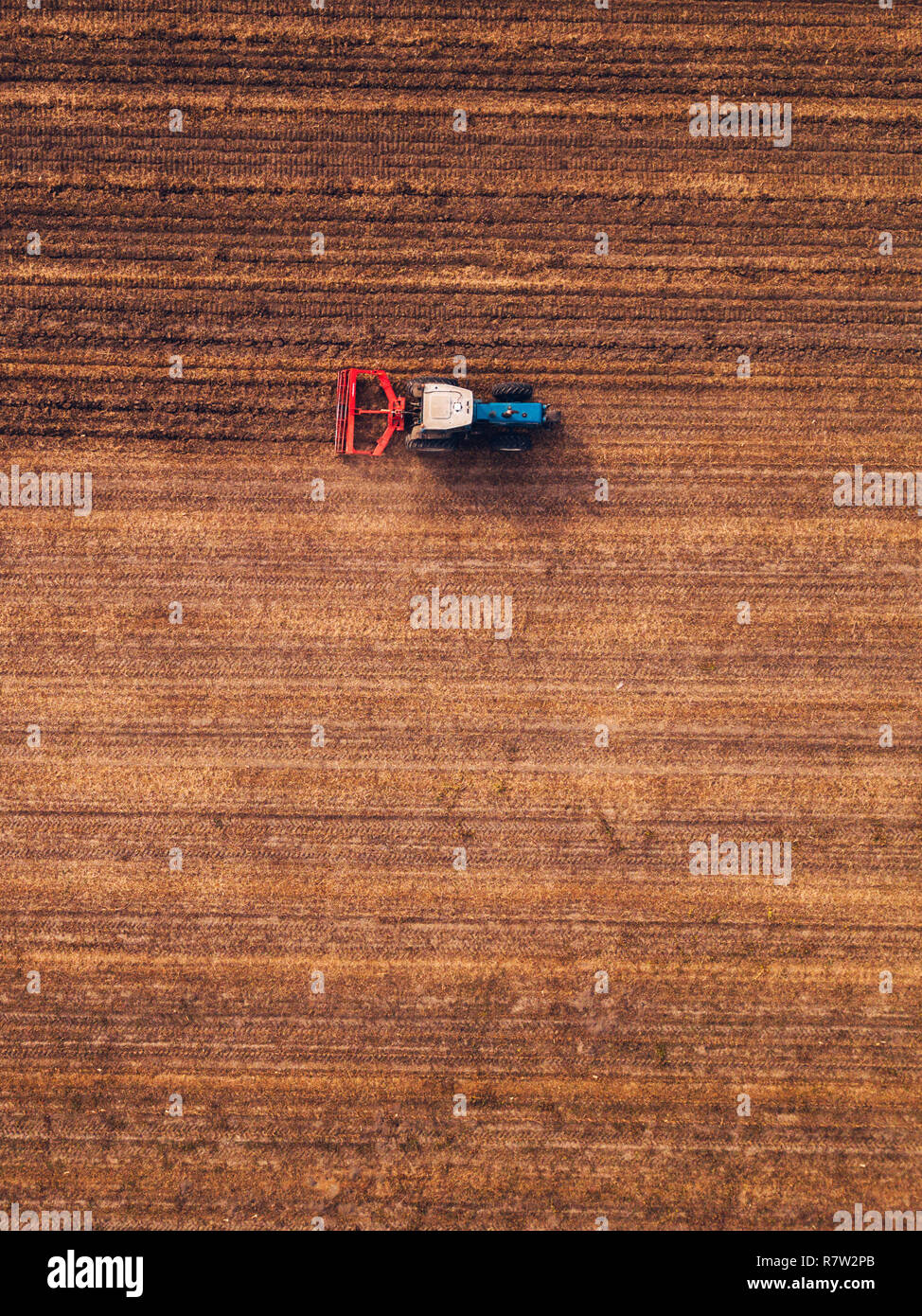 Vista aerea del trattore agricolo facendo dissodamento stoppie nel campo, vista dall'alto da fuco pov Foto Stock