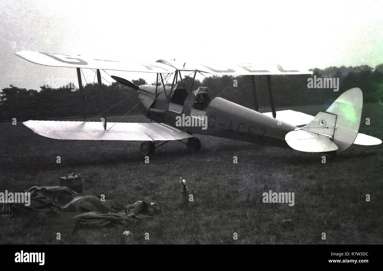 Degli anni Cinquanta, histoirical parcheggiati in un campo, un biplano, a 2 posti Tiger Moth open-cockpit aeoplane (registraton n. G-ACEZ) fatta da de Haviilland negli anni Trenta del Novecento e utilizzato principalmente come un velivolo da addestramento. Probabilmente la migliore formazione knon aereo mai più di 9 mila Tiger falene sono state costruite. Foto Stock