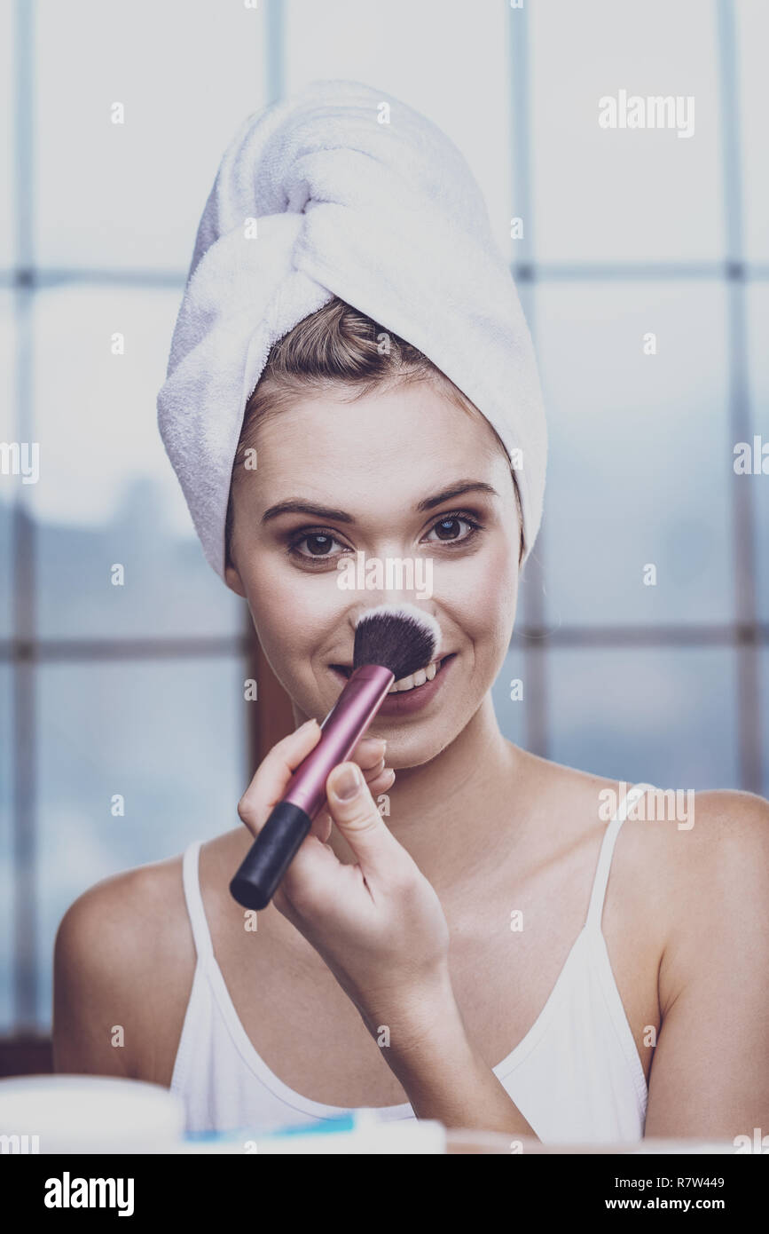 Giovane donna l'applicazione di polvere sul suo naso Foto Stock