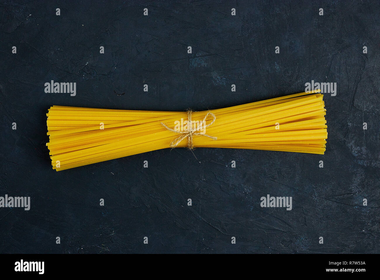 Paste alimentari non cotte legato con una corda su calcestruzzo su sfondo nero. copia spazio. vista dall'alto. Foto Stock