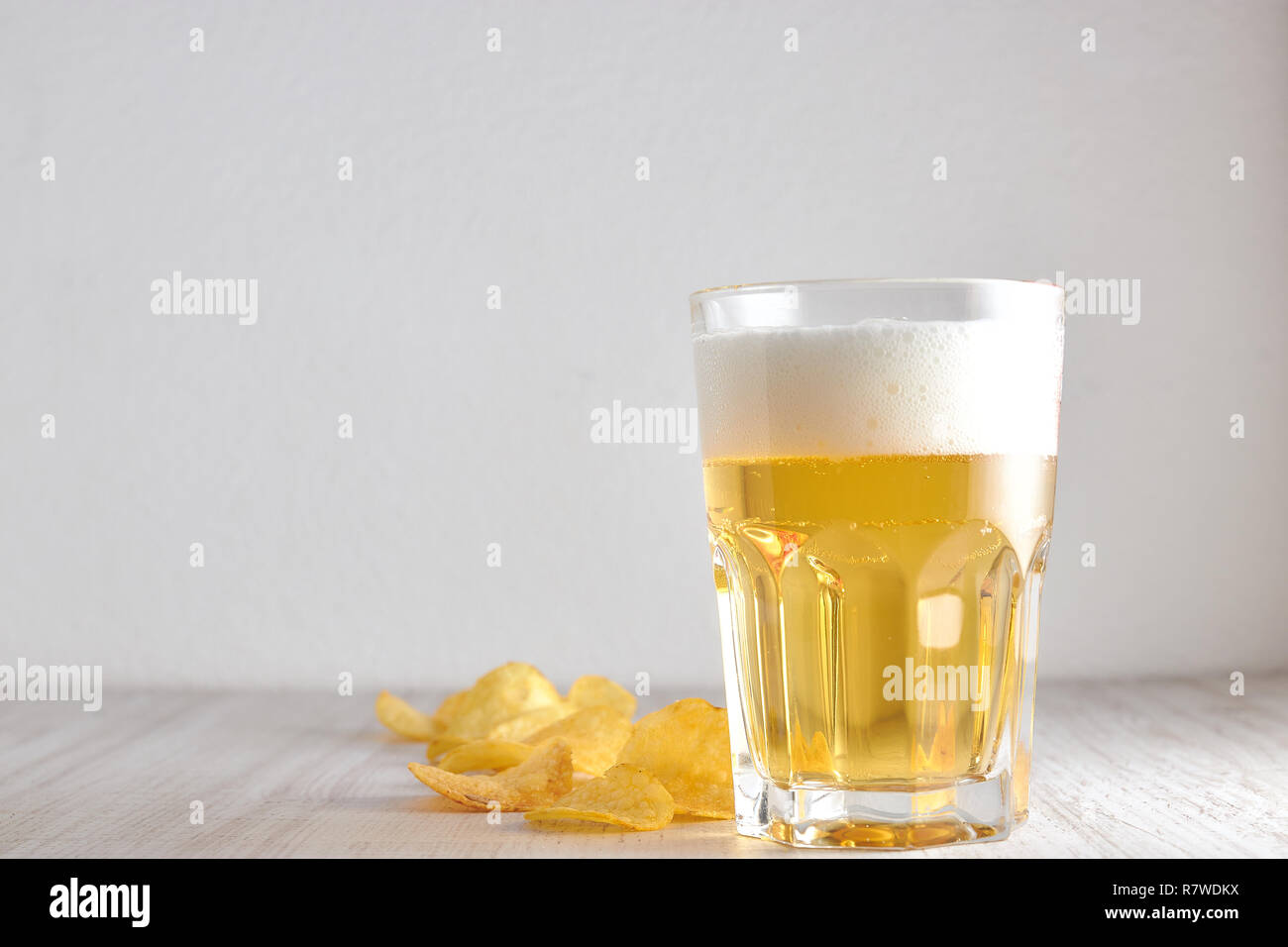 Un vetro a freddo, frumento, birra chiara con trucioli sparsi sul tavolo. copia di spazio. Foto Stock