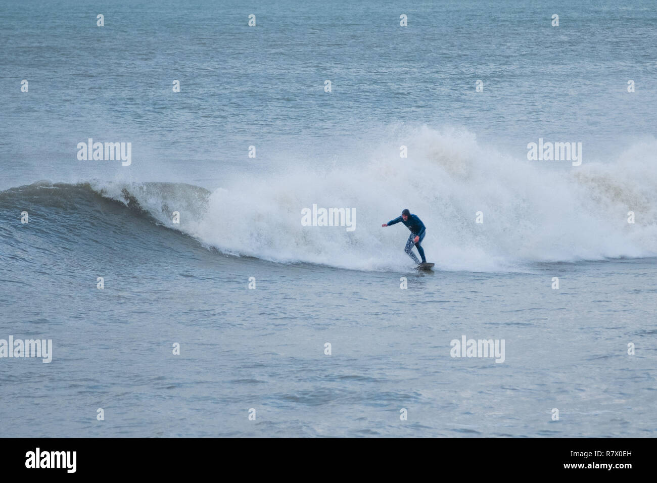 Aberystwyth Wales UK, mercoledì 12 dicembre 2018 UK Meteo: un lone surfer rende la maggior parte della laminazione si gonfiano fuori dalla spiaggia in Aberystwyth Wales, su un grigio e nuvoloso ma molto dolce metà giornata di dicembre. Photo credit: Keith Morris / Alamy Live News Foto Stock
