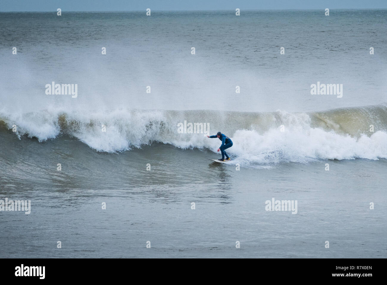 Aberystwyth Wales UK, mercoledì 12 dicembre 2018 UK Meteo: un lone surfer rende la maggior parte della laminazione si gonfiano fuori dalla spiaggia in Aberystwyth Wales, su un grigio e nuvoloso ma molto dolce metà giornata di dicembre. Photo credit: Keith Morris / Alamy Live News Foto Stock
