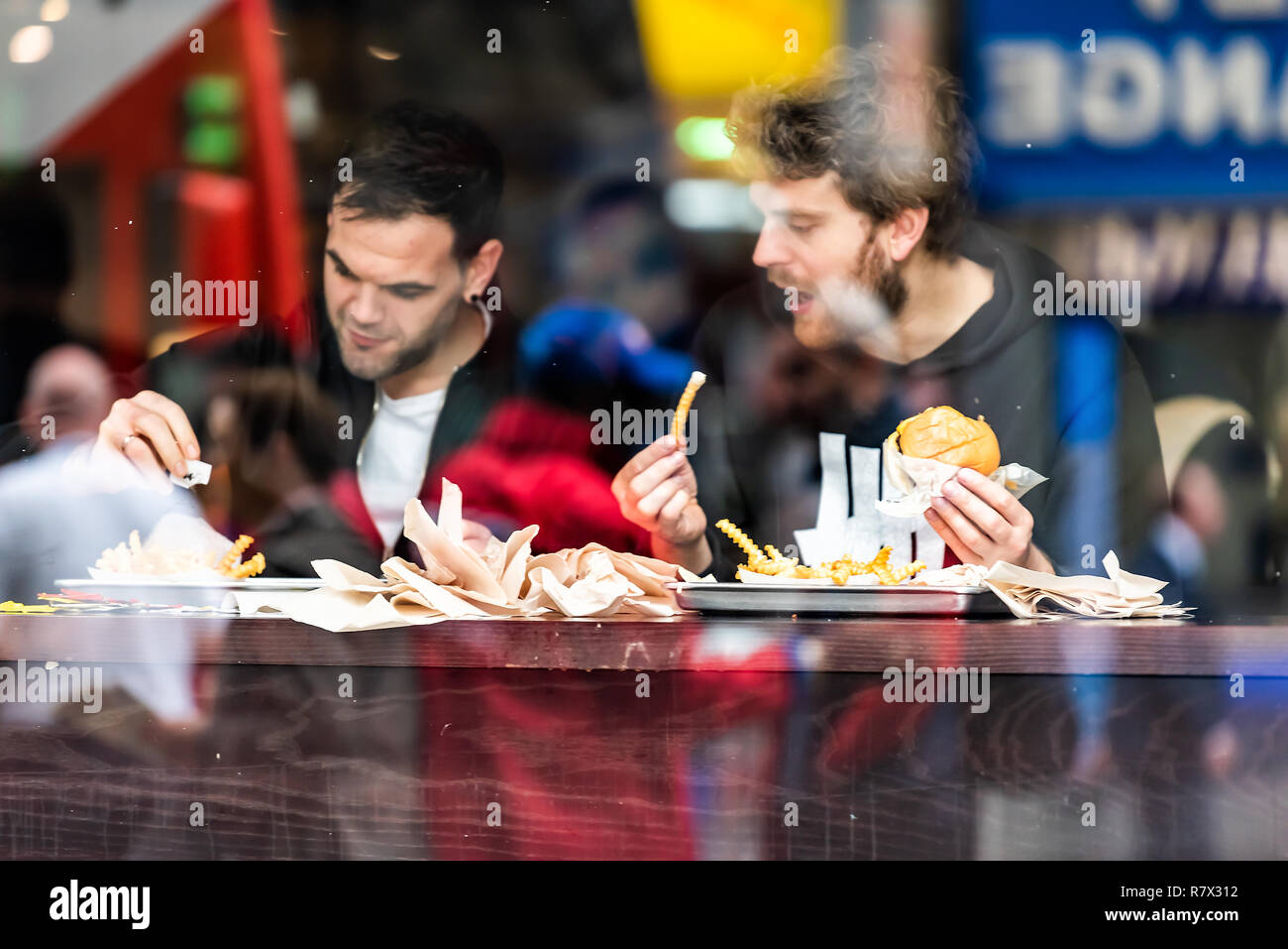 London, Regno Unito - 12 Settembre 2018: due uomini guy amici seduti in un fast food cafe guardando fuori dalla finestra, contatore di riflessione di Brewer street a Brixton Foto Stock