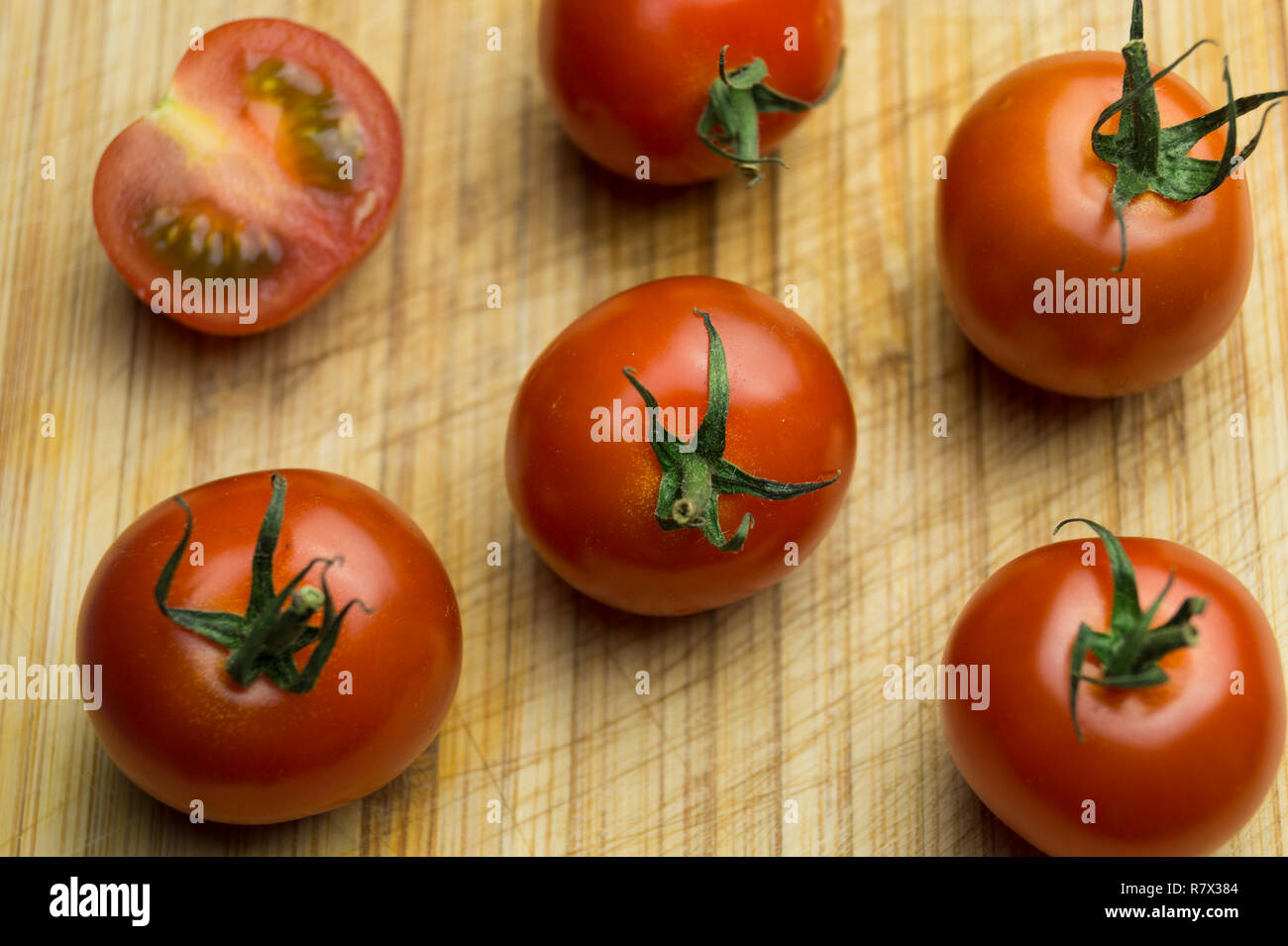 Close-up di piccoli freschi decorativi pomodori rossi su un tavolo di legno. Foto Stock