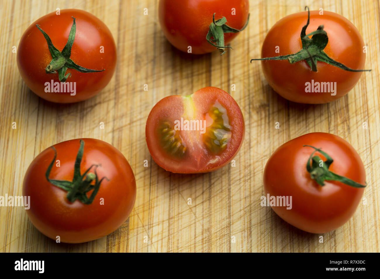 Close-up di piccoli freschi decorativi pomodori rossi su un tavolo di legno. Foto Stock