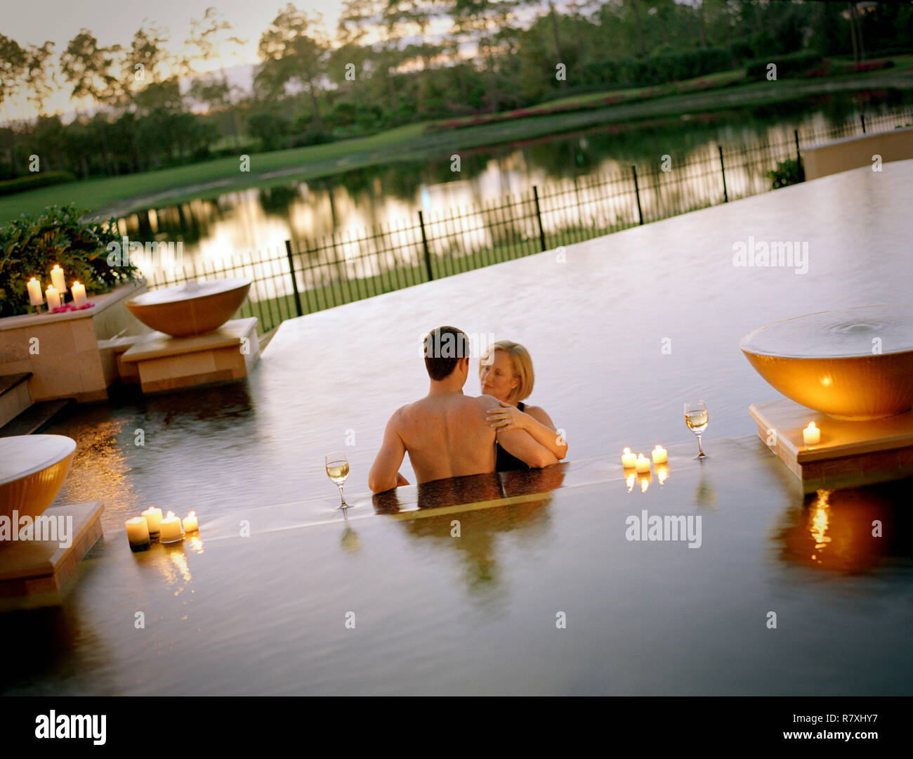 Donna matura rivolta verso il suo partner in una candela accesa piscina. Foto Stock