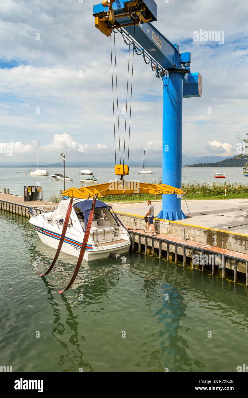 BARDOLINO, LAGO DI GARDA, Italia - Settembre 2018: Remote gru controllata spostando la sua culla e le cinghie dopo aver abbassato un motore in acqua a una marina Foto Stock