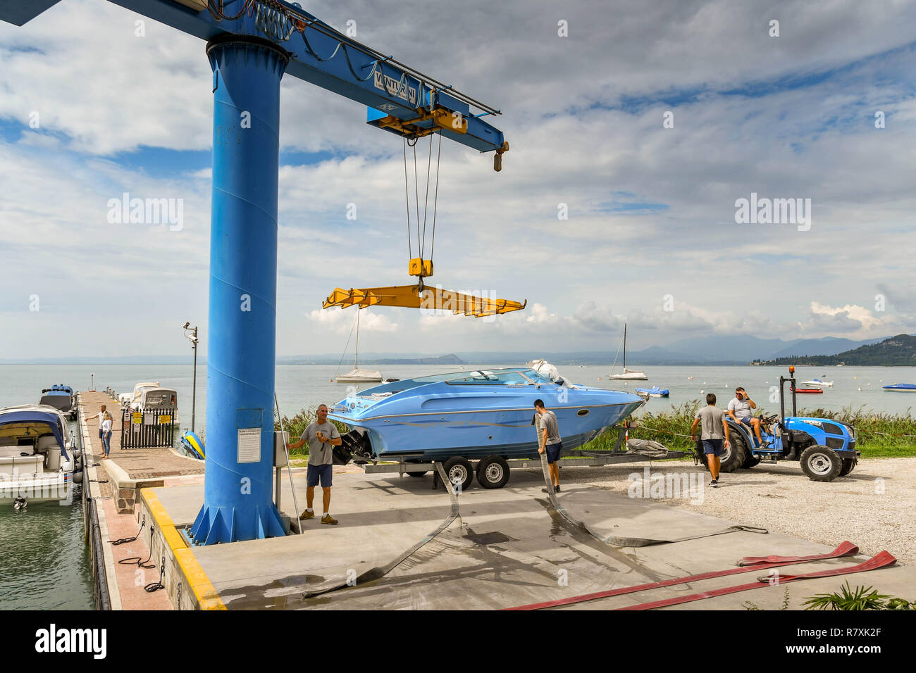 BARDOLINO, LAGO DI GARDA, Italia - Settembre 2018: lavoratore operando un telecomando per gru per il sollevamento di una barca in acqua a un porto turistico sul Lago di Garda vicino Foto Stock