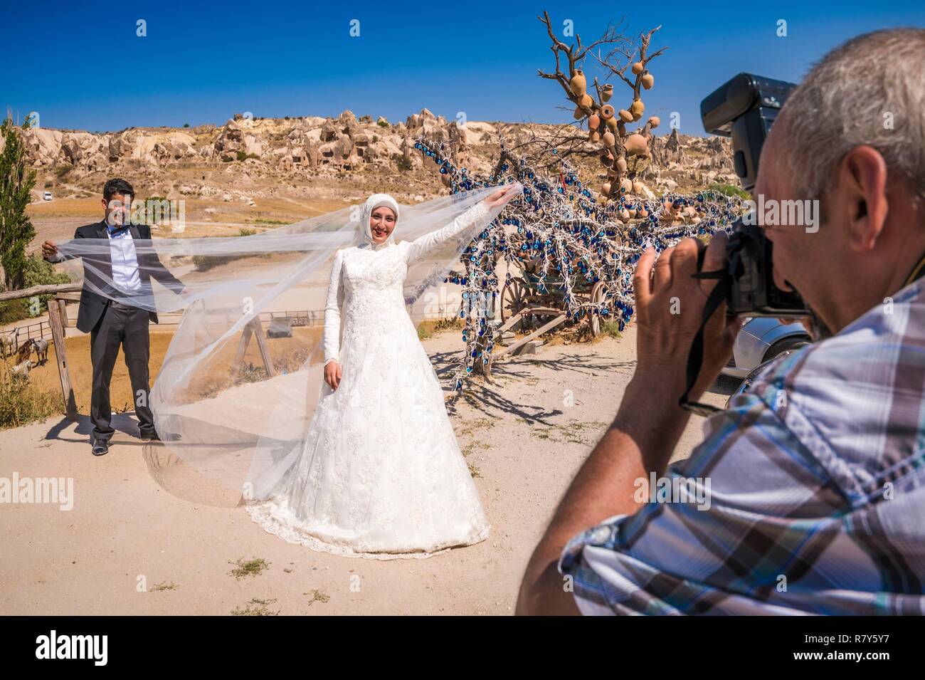 Turchia, Anatolia centrale, Nevşehir provincia, Cappadocia UNESCO World Heritage Site, Göreme, sposi novelli costituiscono per loro fotografo di fronte al paesaggio iconica al tufo vulcanico colline del Parco nazionale di Göreme Foto Stock
