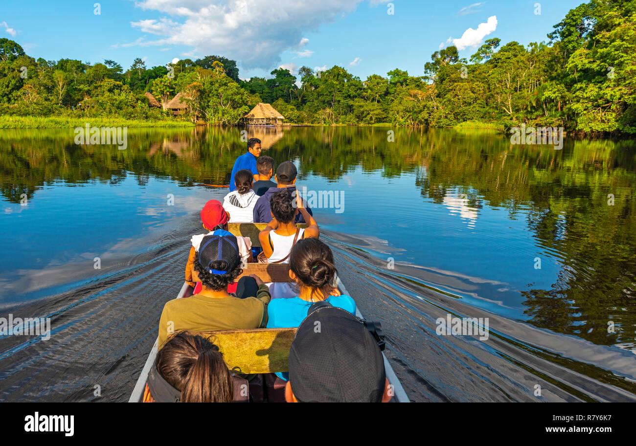Trasporto in canoa lungo i fiumi del bacino del Rio delle Amazzoni all'interno del Parco Nazionale di Yasuni con un Lodge in stile architettonico tradizionale, Ecuador. Foto Stock