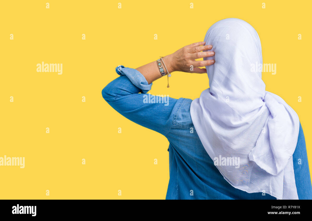 La mezza età araba orientale donna che indossa arabian hijab su sfondo isolato indietro pensando di dubbio con la mano sulla testa Foto Stock