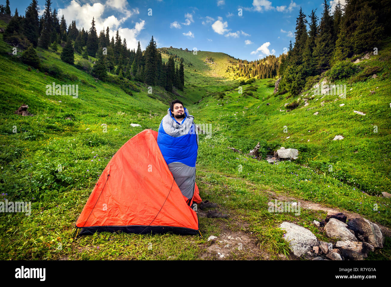 Turista nel sacco a pelo vicino a Orange tenda in montagna in Kazakistan e in Asia centrale Foto Stock
