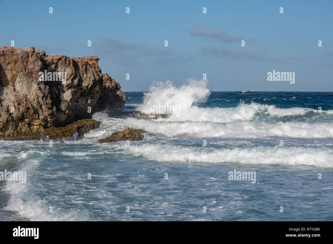 Onde si infrangono in un dirupo - acquamarina e il blu delle onde che si infrangono sulla battigia in rocce sulla costa di Aruba - Dos playa beach nel parco nazionale di Arikok Foto Stock