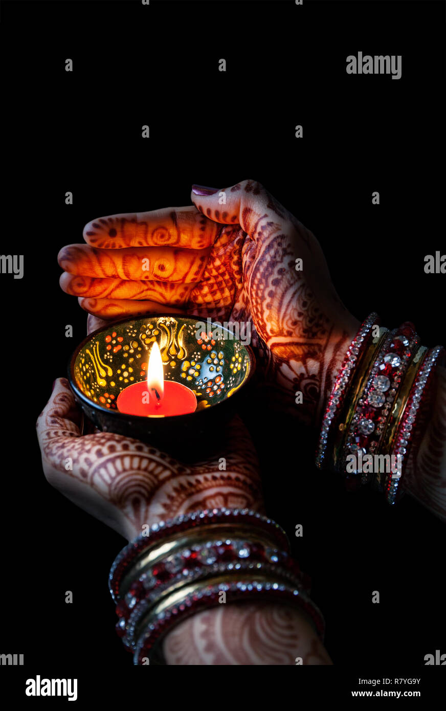 Donna mani con henna tenendo accesa la candela isolata su sfondo nero con tracciato di ritaglio Foto Stock