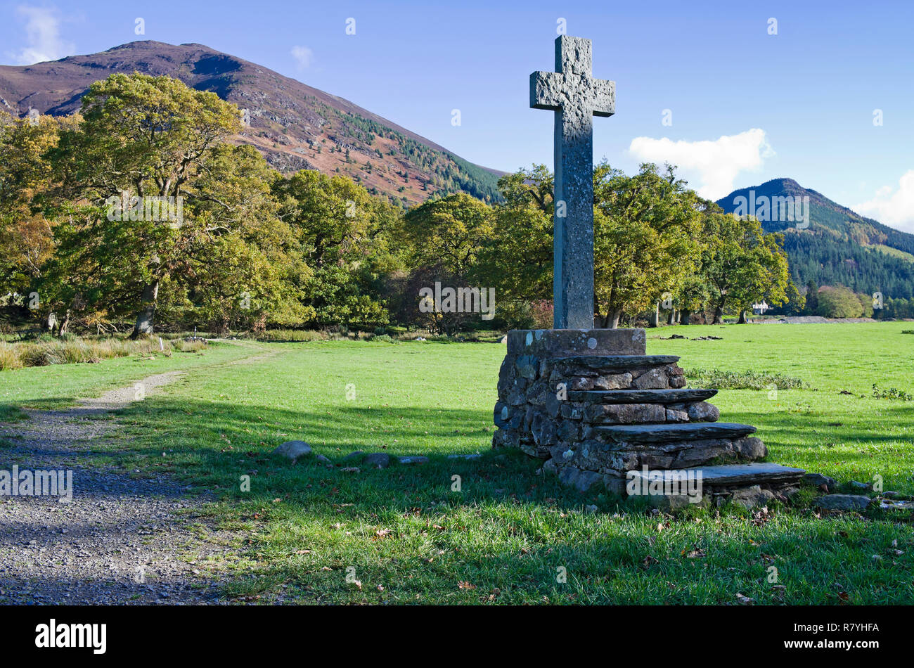 Antica croce di pietra montata su rustico in pietra passi in campo da St Bega la chiesa di Bassenthwaite, Ullock Pike e Dodd crescente dietro, Lake District, Cumbria Foto Stock