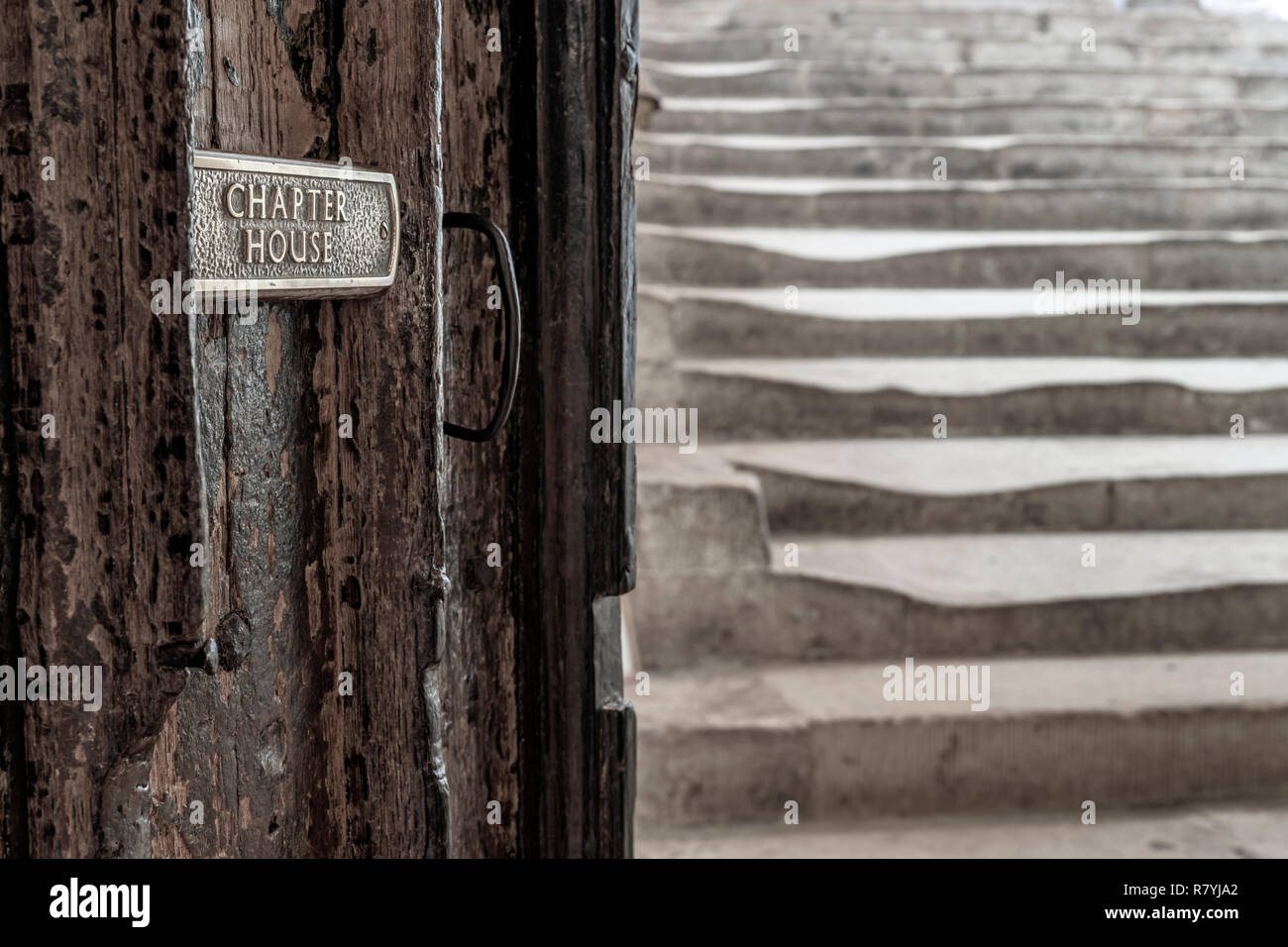 Un piccolo segno sulla antica porta in legno che mostra la via per la storica Aula Capitolare passi alla Cattedrale di Wells nel Somerset. Foto Stock