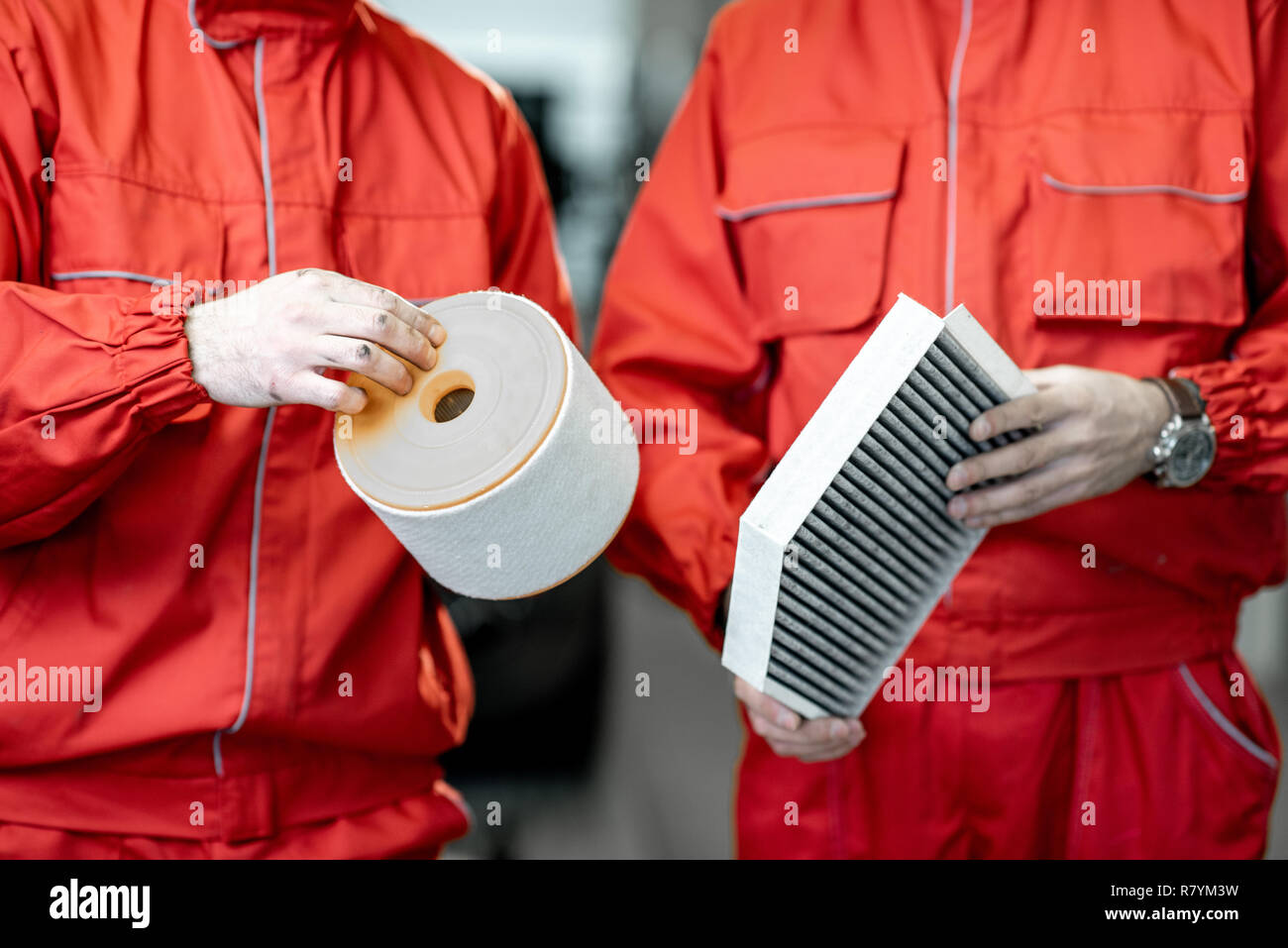 Meccanico automatico in rosso uniforme tenendo premuto di nuovo e usato il filtro dell'aria permanente al car service Foto Stock