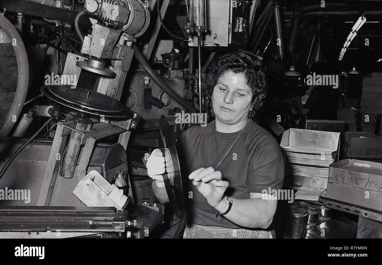 Anni Settanta, storico, il lavoratore di sesso femminile in un impianto di fabbricazione utilizzando macchinari per stampa in vinile record, STATI UNITI D'AMERICA. Foto Stock