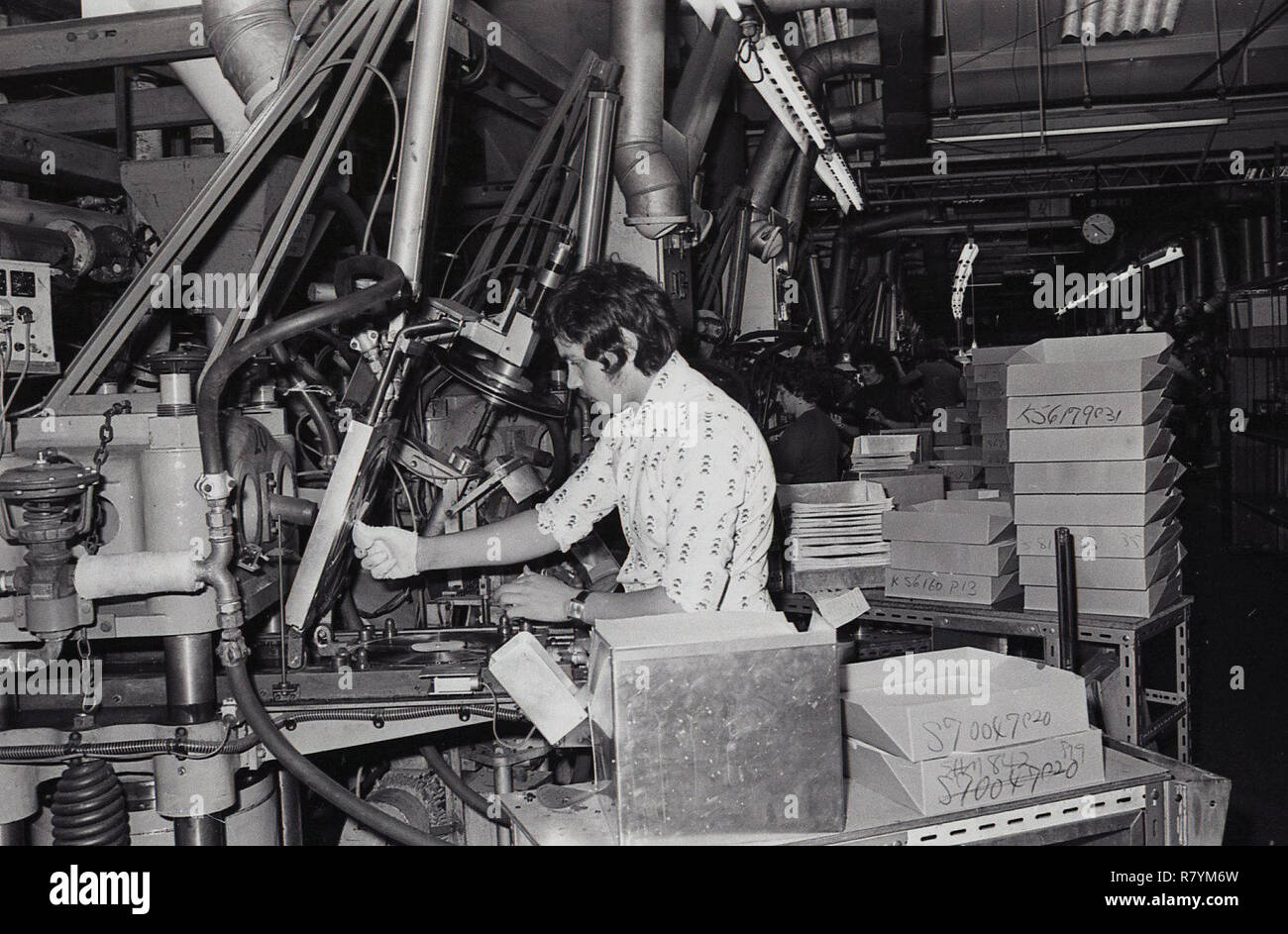 Anni Settanta, storico, un lavoratore di sesso maschile in un impianto di produzione utilizzando un macchinario per lo stampaggio di dischi in vinile, STATI UNITI D'AMERICA. Foto Stock