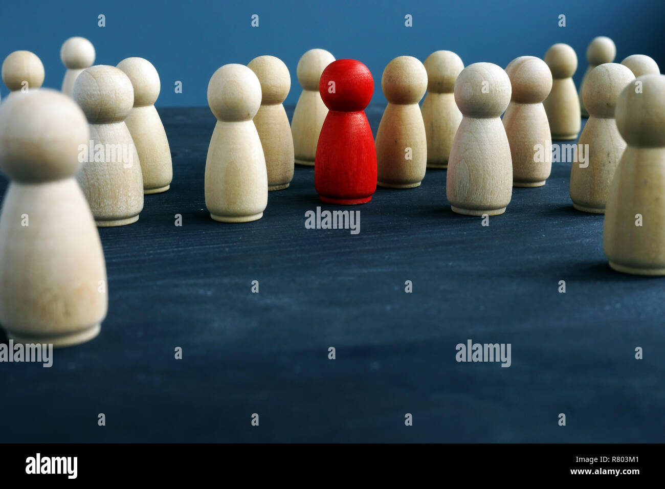 Figure in legno e uno rosso figura. Essere diversi. Distinguiti dalla folla. Foto Stock