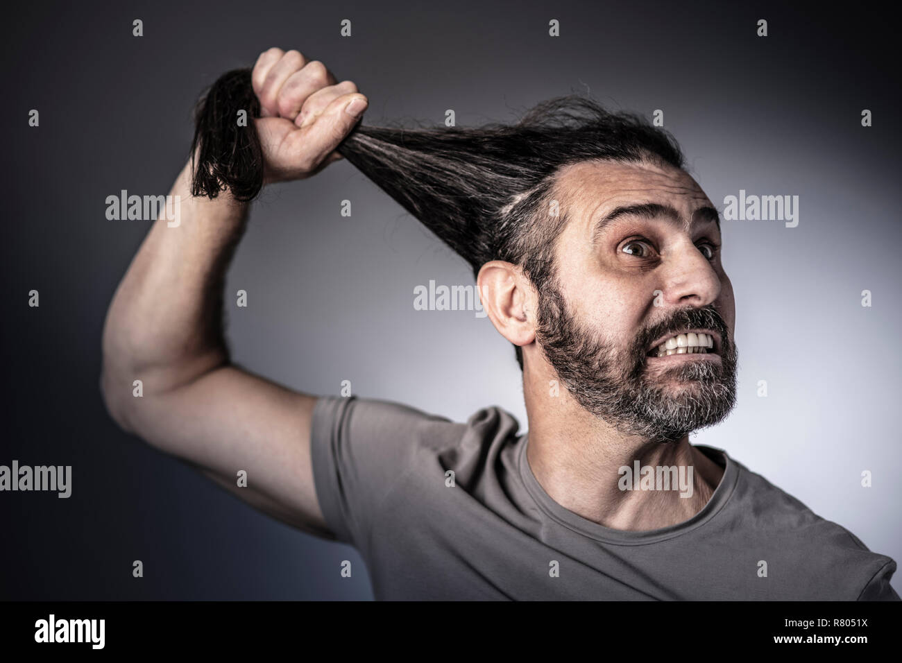 Concetto di rabbia, man tenere i suoi lunghi capelli in mano studio shot Foto Stock