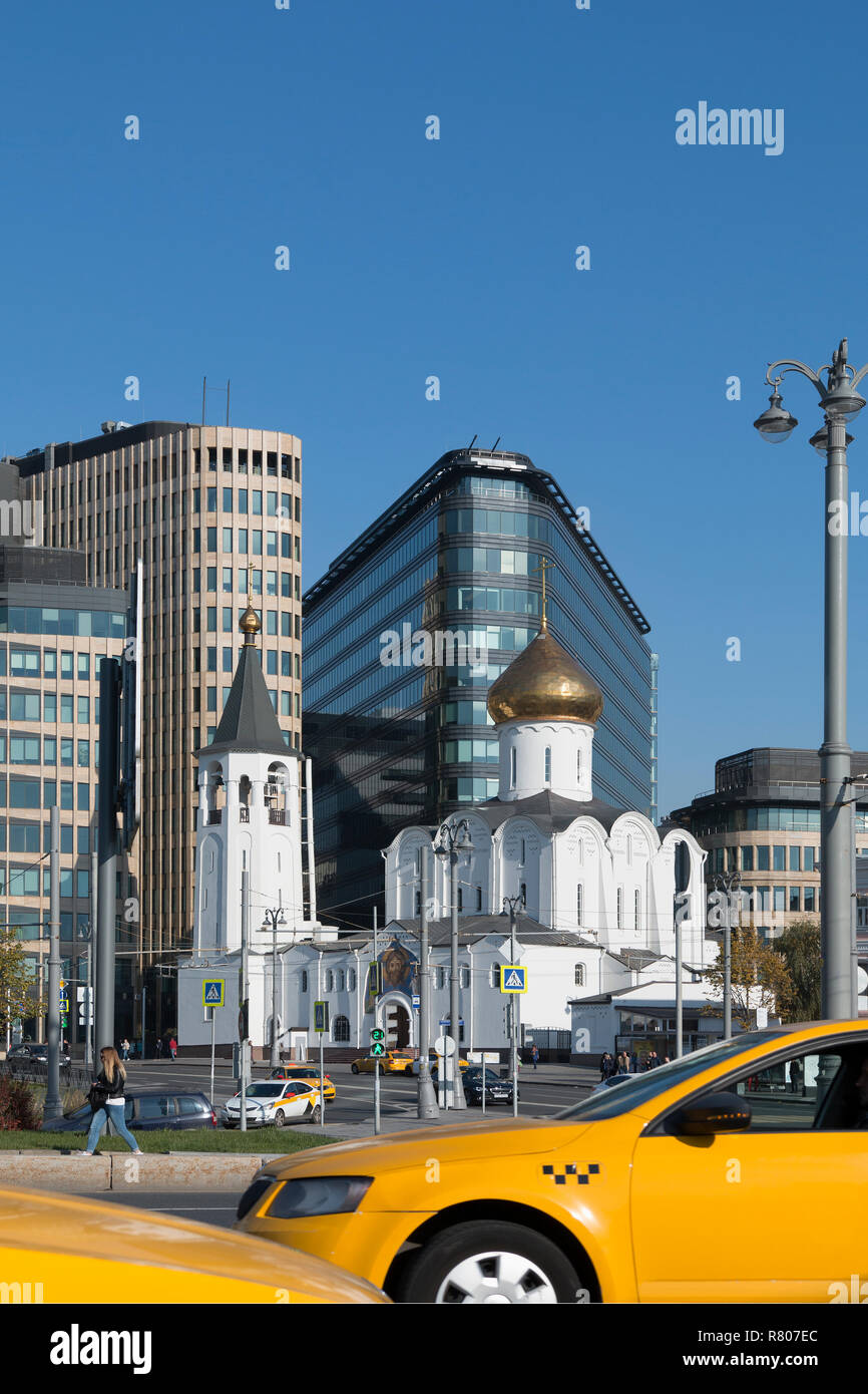 Vecchia chiesa bianca sullo sfondo della città moderna e due per il giallo taxi. Mosca - Ottobre 2018 Foto Stock