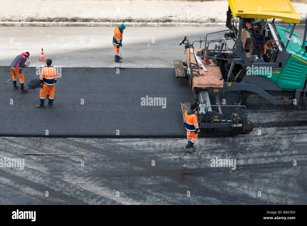 Asfalto lastricatore della macchina su strada e lavoratori edili sulla strada sito di riparazione. Strada al processo di rinnovo, il lavoro di costruzione. Elevato angolo di visione Foto Stock