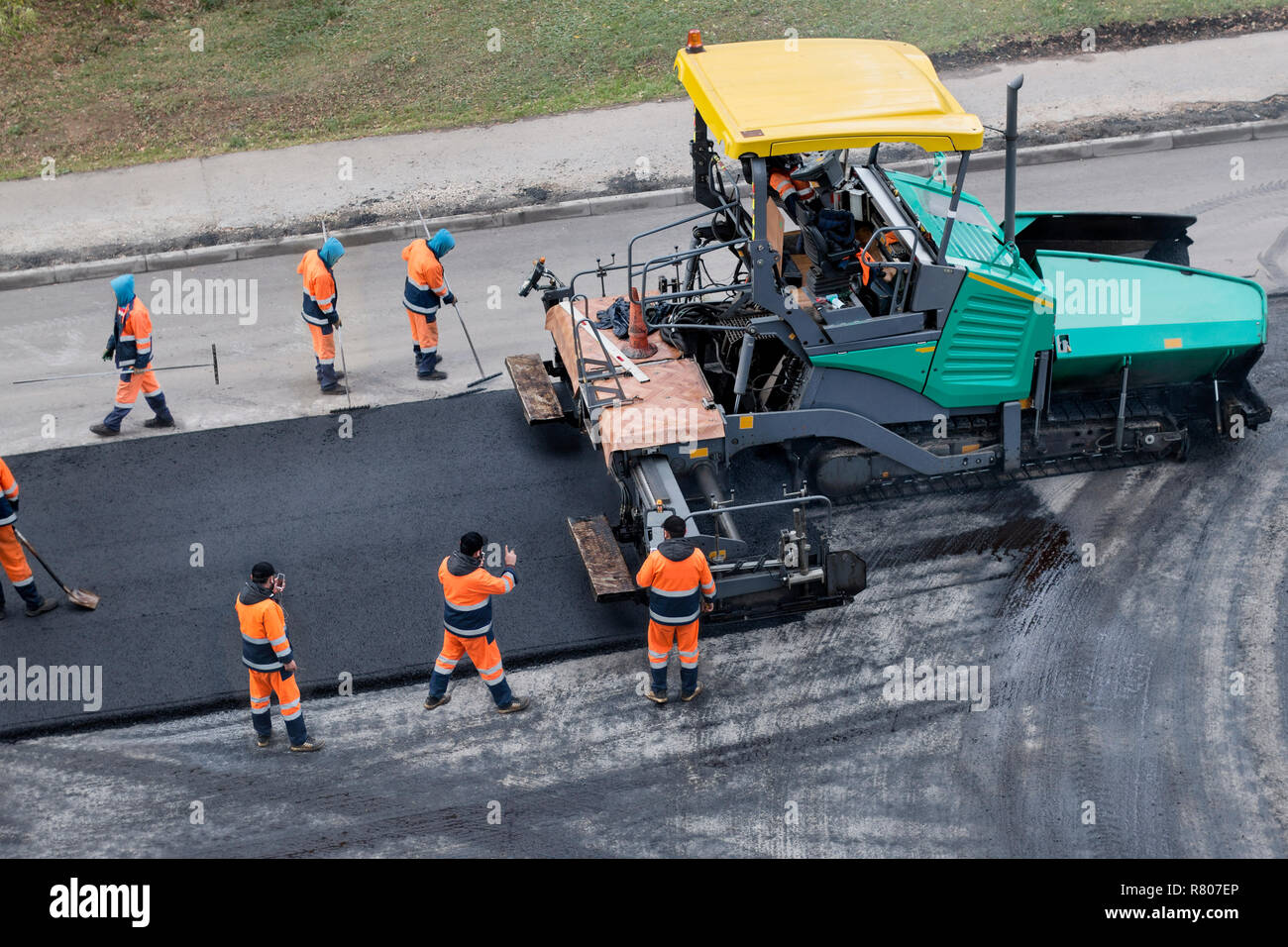 Asfalto lastricatore macchina o unità di finitura lastricatore luoghi uno strato di asfalto fresco. Strada al processo di rinnovo, il lavoro di costruzione. Il collage, irriconoscibile lavoratori. Foto Stock