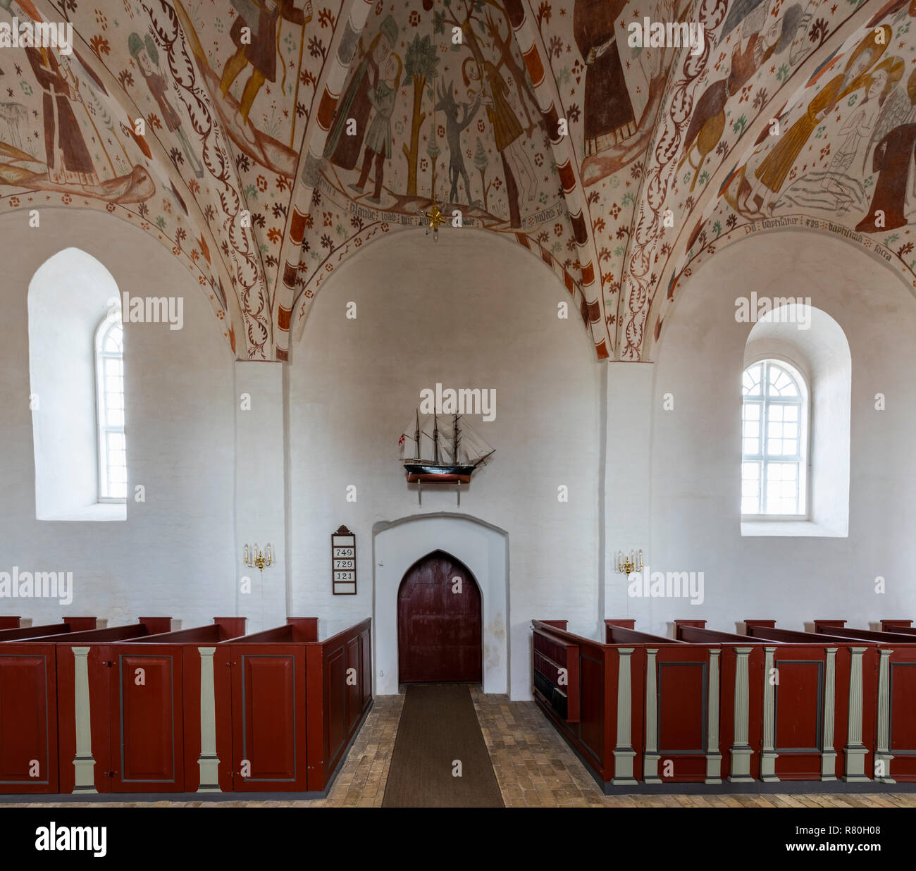 Mon, Danimarca - 17 Settembre 2018: Interno della chiesa Fanefjord con colorati soffitti con affreschi, un modello di una nave di pescatori a parete e rosso, Foto Stock