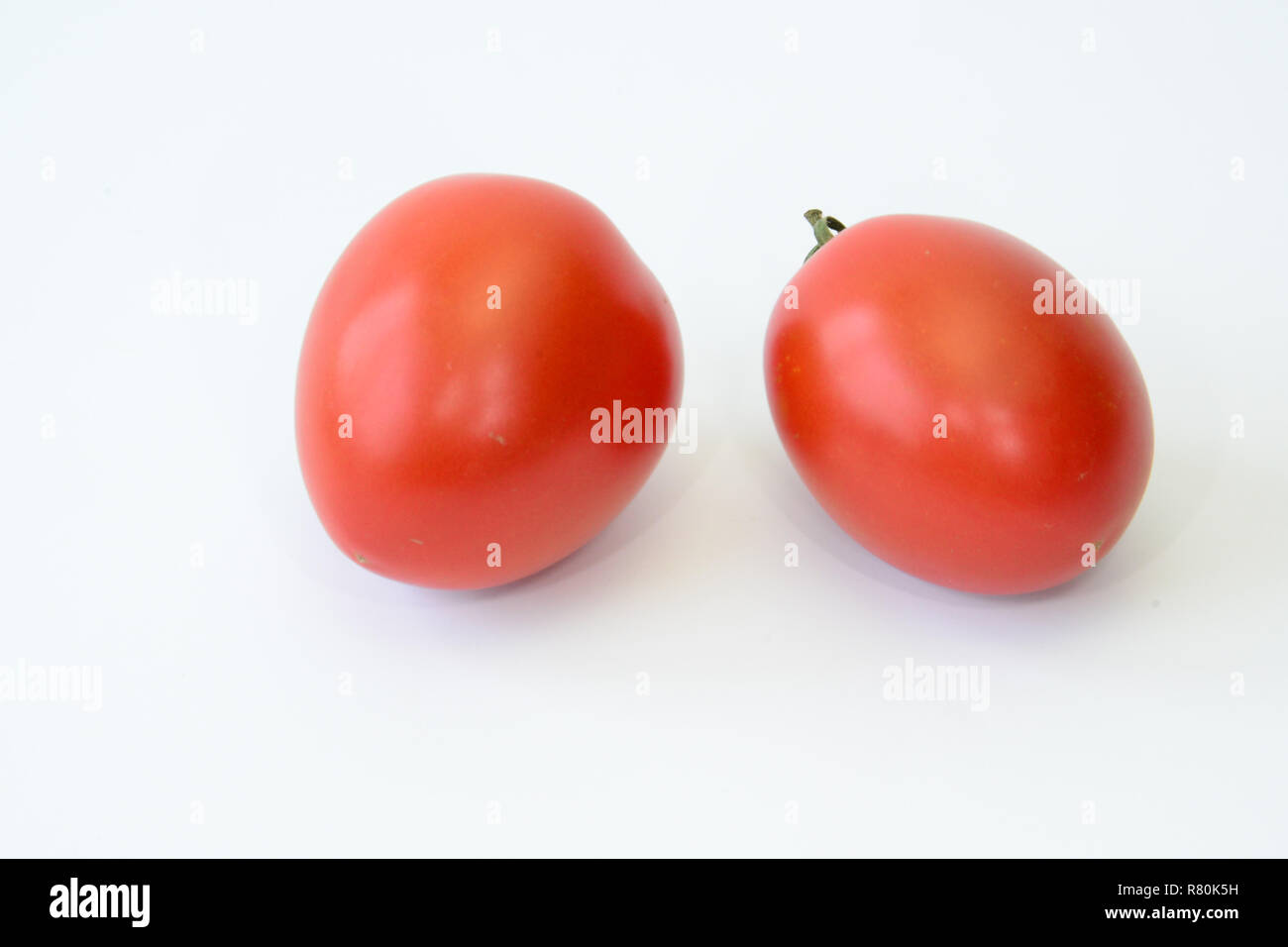 (Pomodoro Solanum lycopersicumm), varietà: Roma, Italiano prugna pomodoro. Due frutti maturi. Studio Immagine contro uno sfondo bianco Foto Stock
