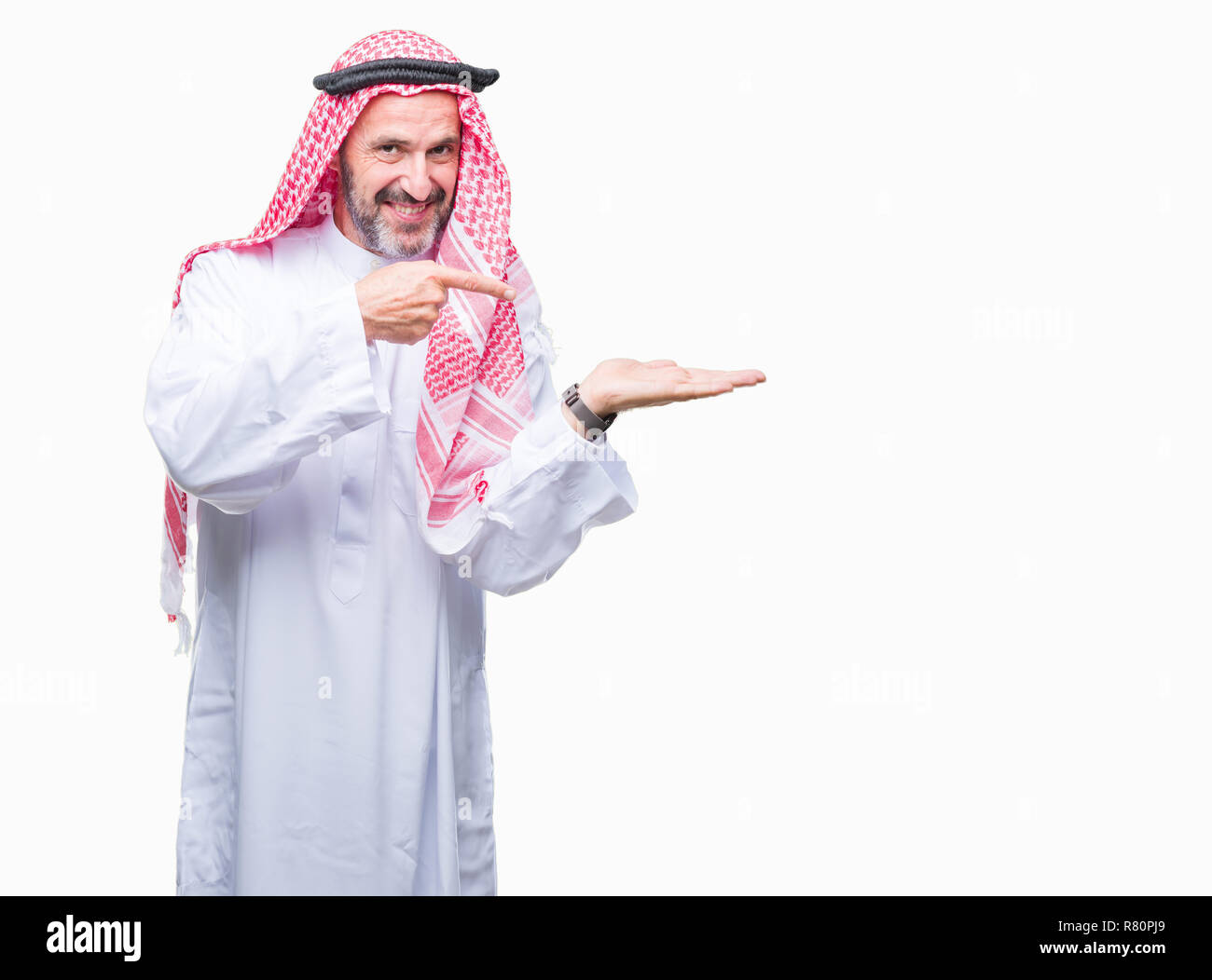 Senior uomo arabo indossando keffiyeh su sfondo isolato stupiti e sorridente alla fotocamera durante la presentazione con la mano e puntando con il dito. Foto Stock