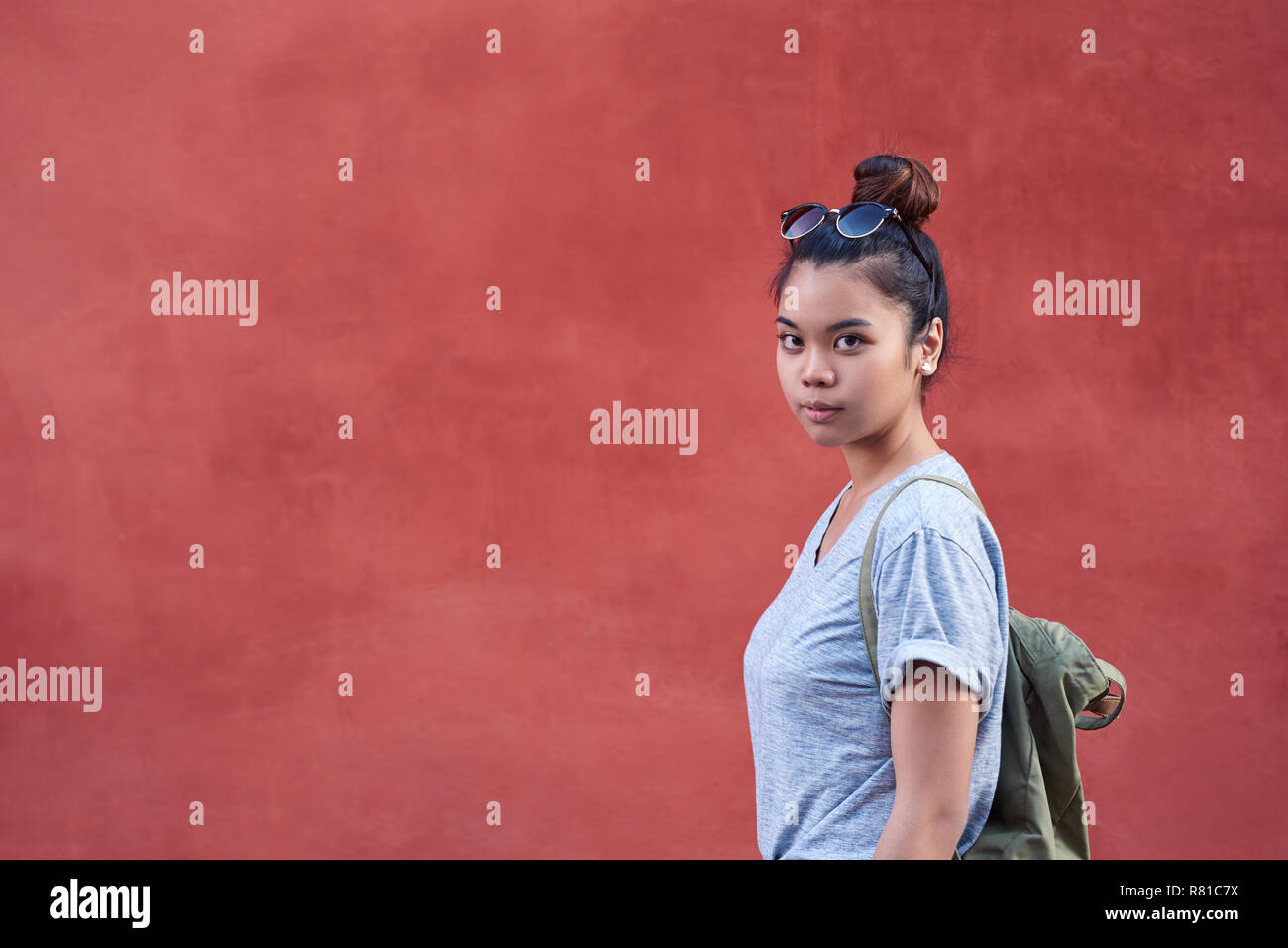 Giovane donna asiatica in piedi di fronte a un muro esterno Foto Stock