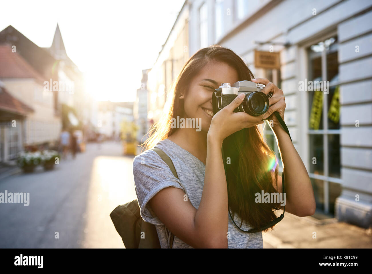 Sorridente giovane donna asiatica di scattare le foto in città Foto Stock