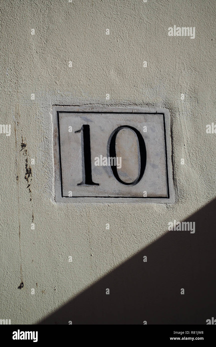 Numero dieci su una lapide di marmo su una parete di gesso Foto Stock